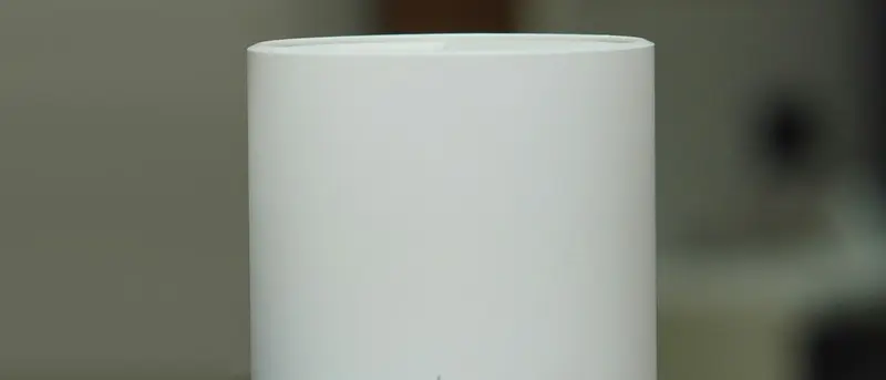 Witte mesh-wifi-unit op een donkere kast
