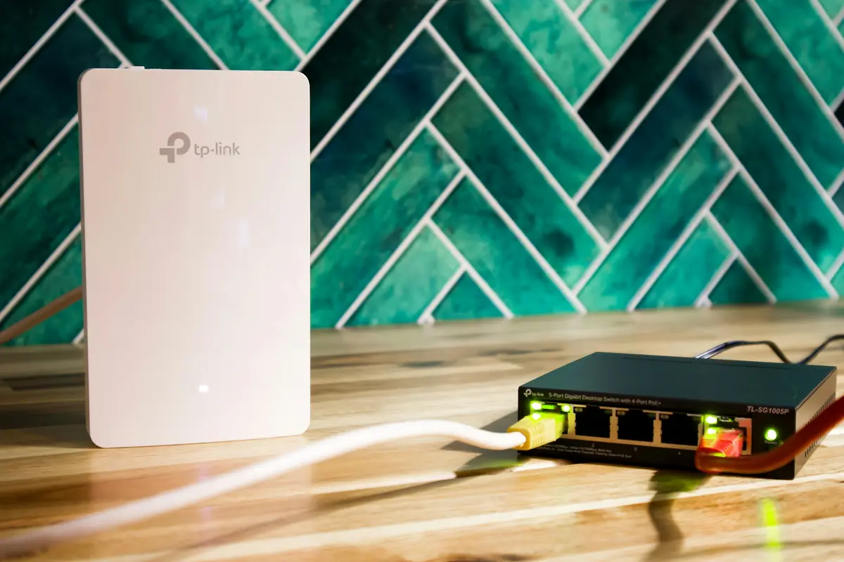 TP-Link accesspoint naast een PoE-switch met een UTP-kabel