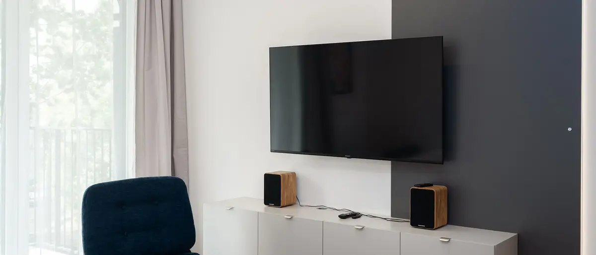 Lichte woonkamer met een tv aan de muur boven een laag tv-meubel